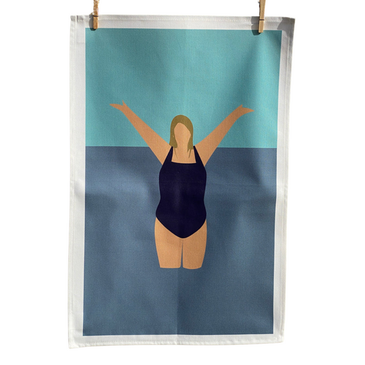 Wild Swimming Tea Towel hanging by pegs on white background.