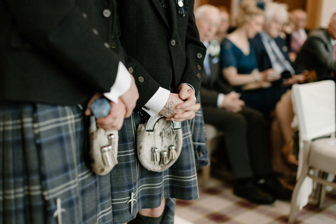 Two men standing in kilts at a wedding.