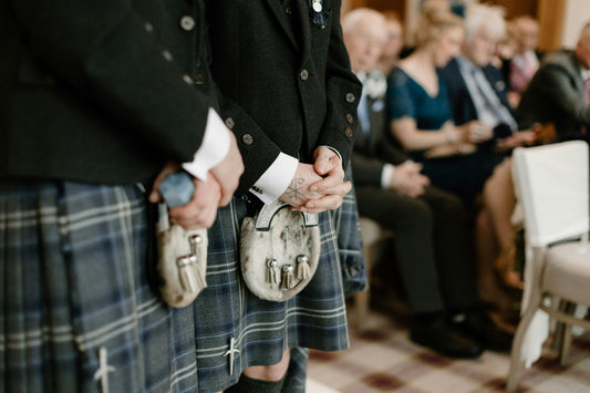 Two men standing in kilts at a wedding.