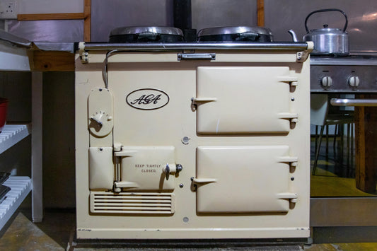 Cream AGA in kitchen with open shelves with stainless steel kettle.