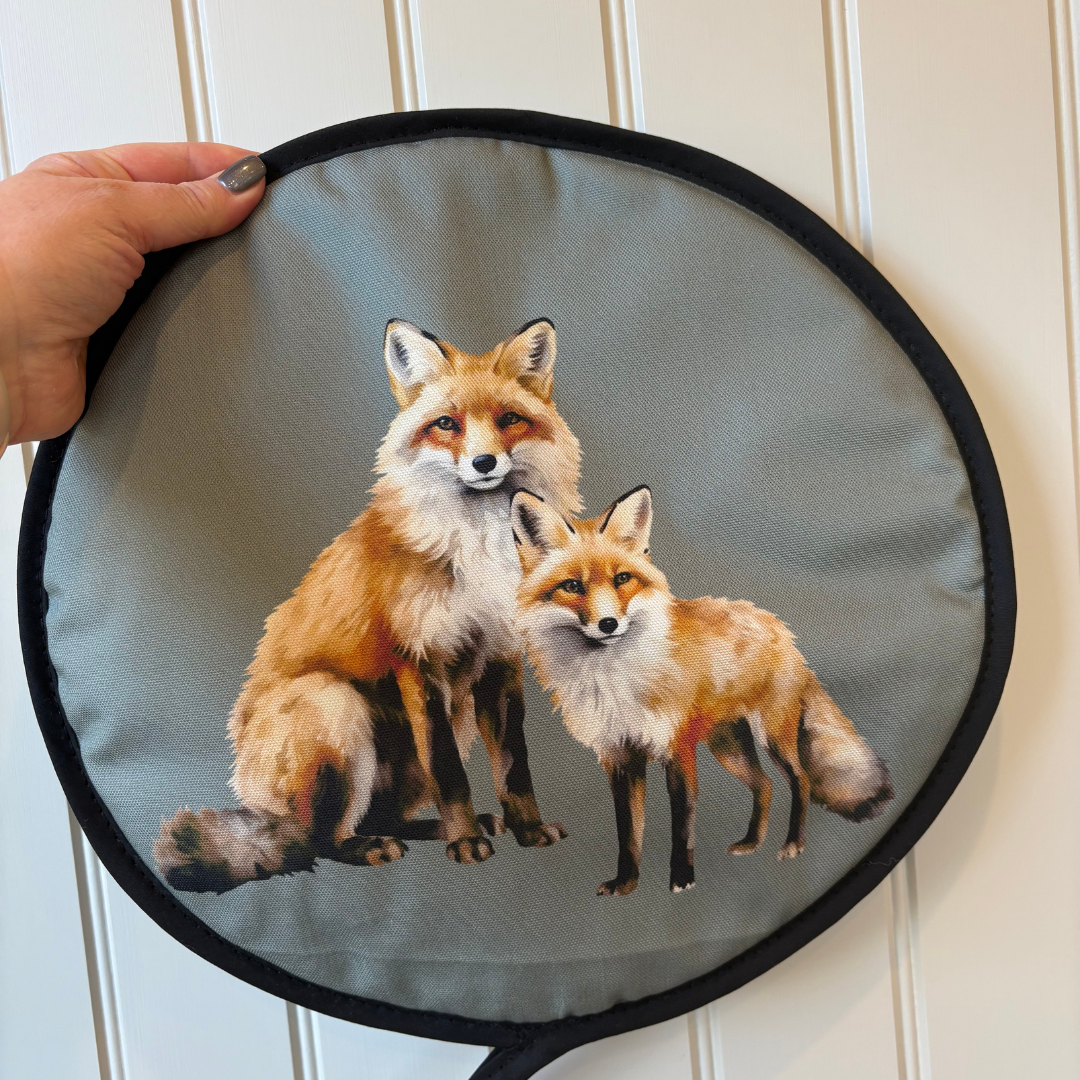 Fox Chef's Pads For AGA being held in hand against a white wall. Stunning countryside design perfect for gifting.