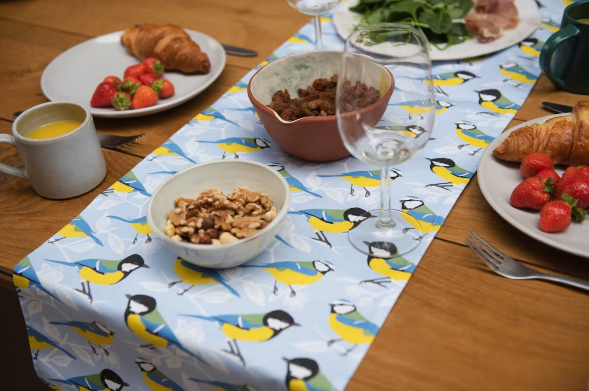 Garden Bird Table Runner on table with plates of food, mugs and glasses.  