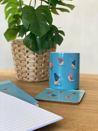 Wild Ones Wild Swimming Mug on wooden desk with plant, coaster and notebook.  