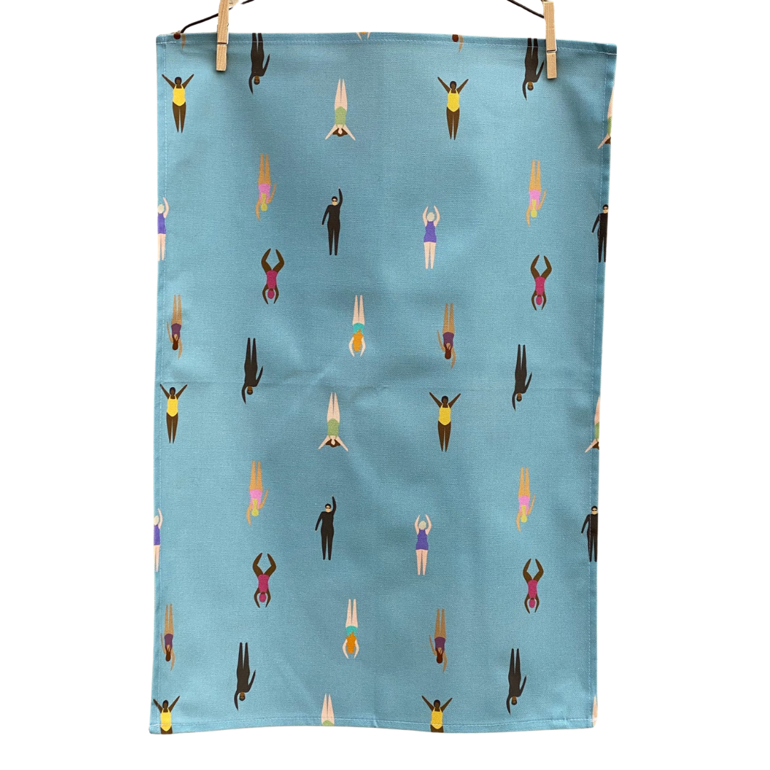 Wild Swimming Tea Towel hanging by pegs on white background.